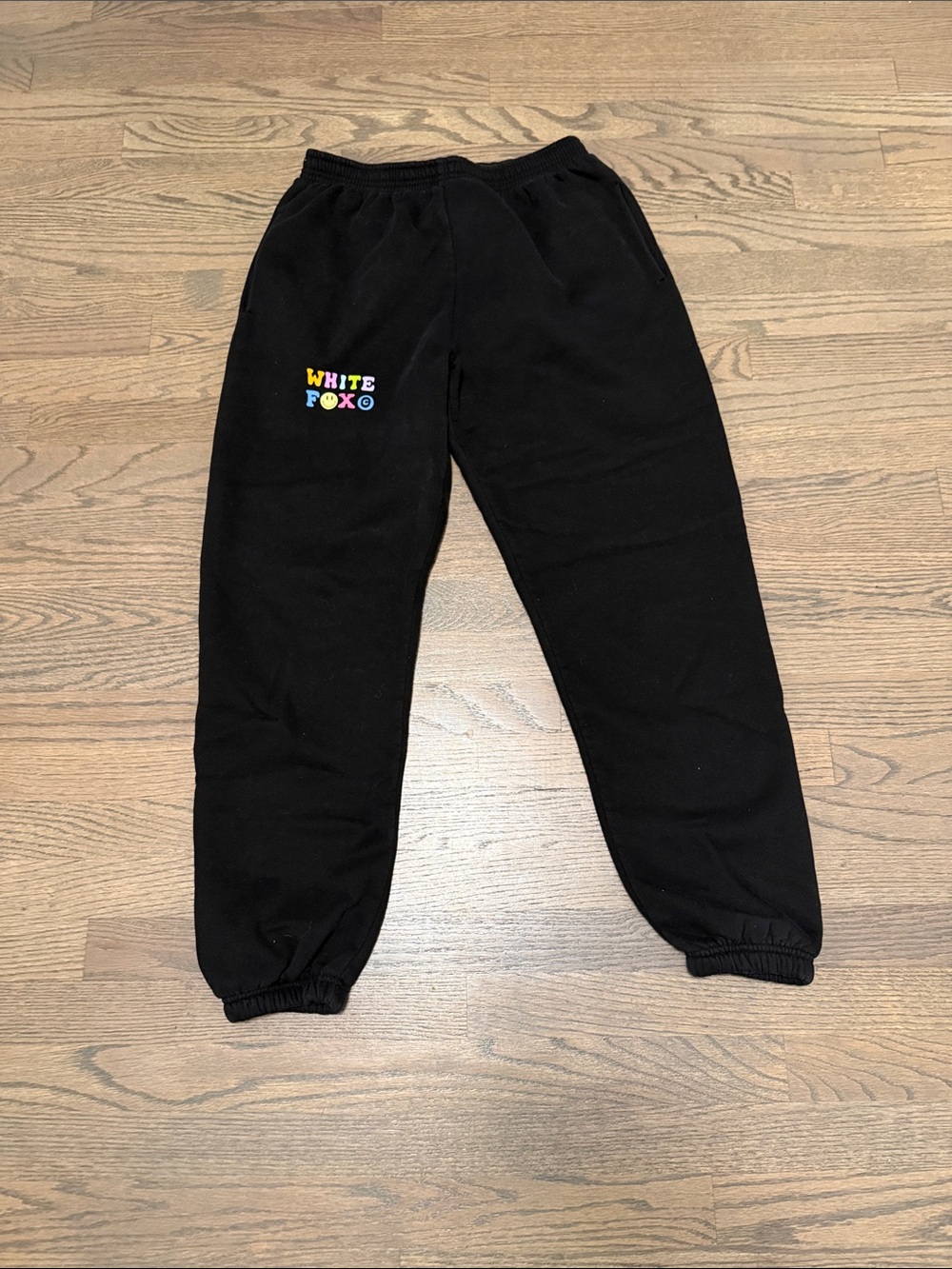 White Fox Women’s Black Sweatpants with Colorful Logo on right hip. Size medium.